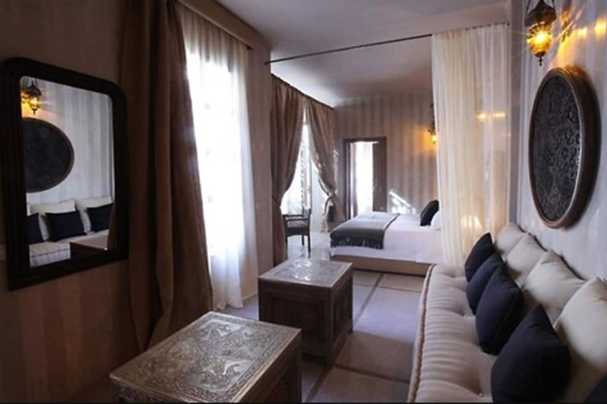 A modern hotel room with a sofa, a coffee table, and a large mirror.