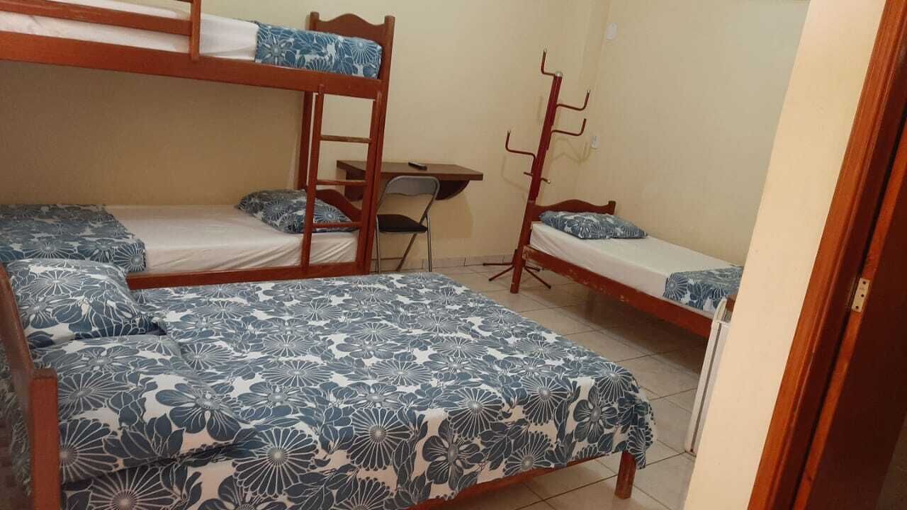 A dormitory room with bunk beds, a desk, and a chair.