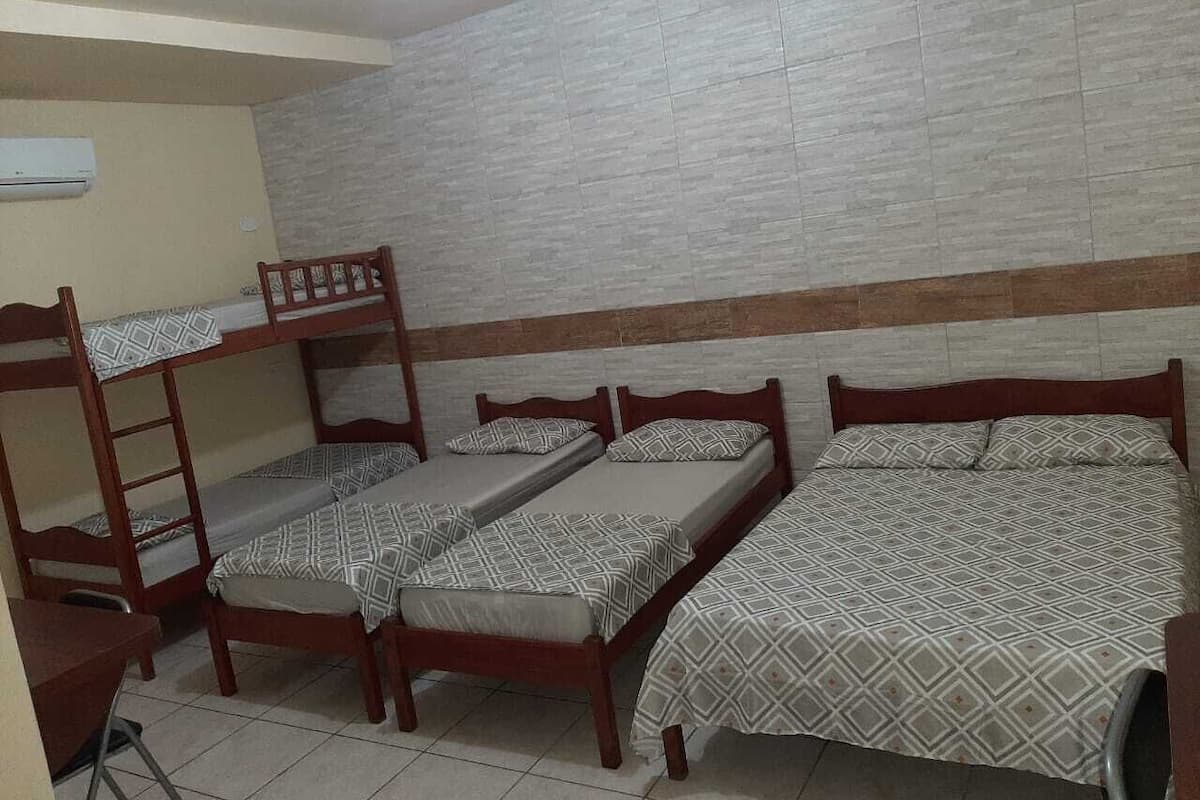 A dormitory room with bunk beds, a desk, and a tiled floor.