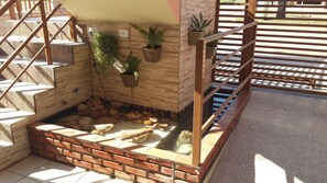 A staircase with a brick base, wooden steps, and a metal railing. There are potted plants on the wall and a small water feature at the bottom. - Pousada Paraiso (Bonito)