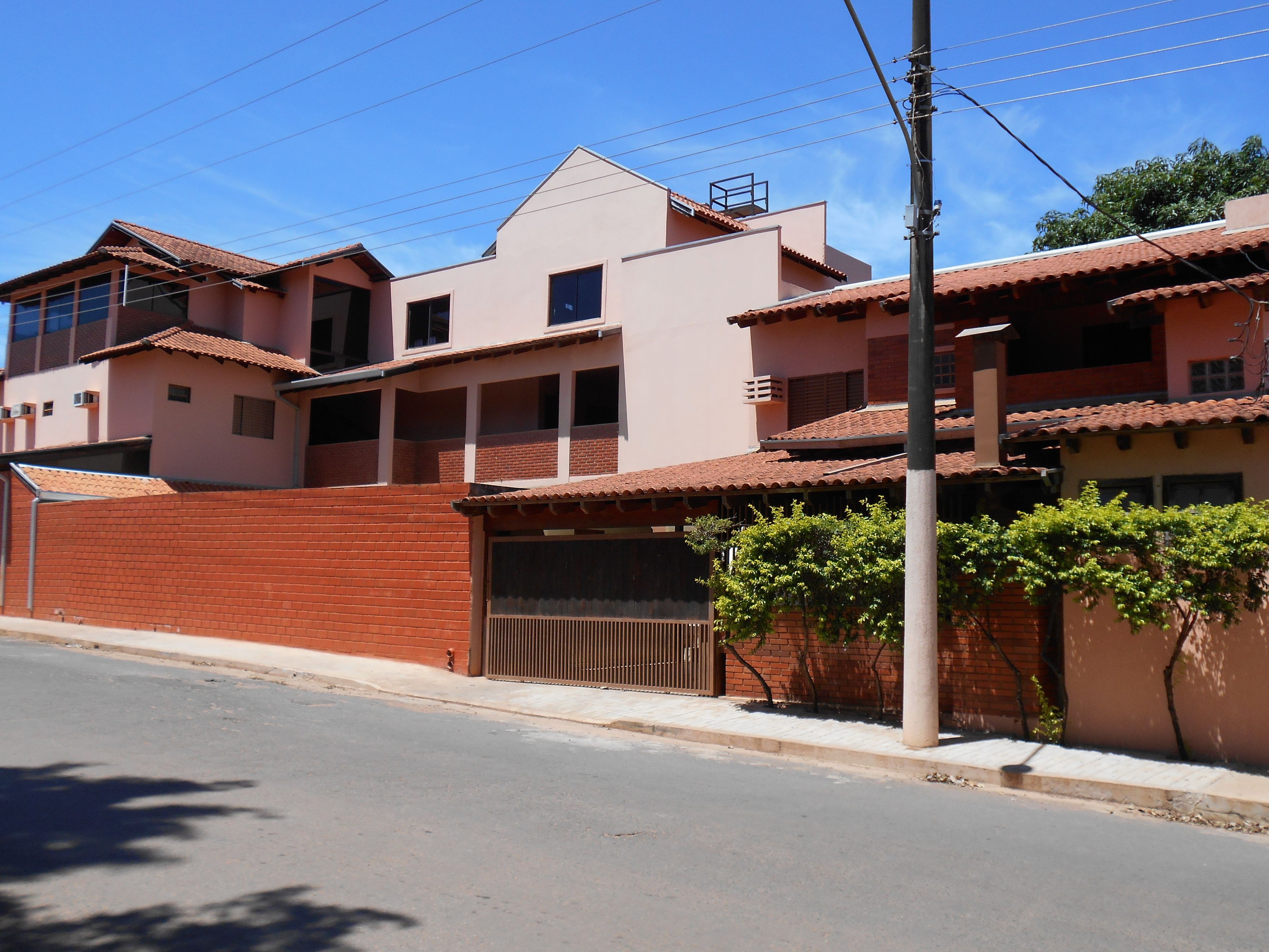 Un edificio residencial de varios pisos con fachada de ladrillo rojo, varios balcones y una entrada con reja.