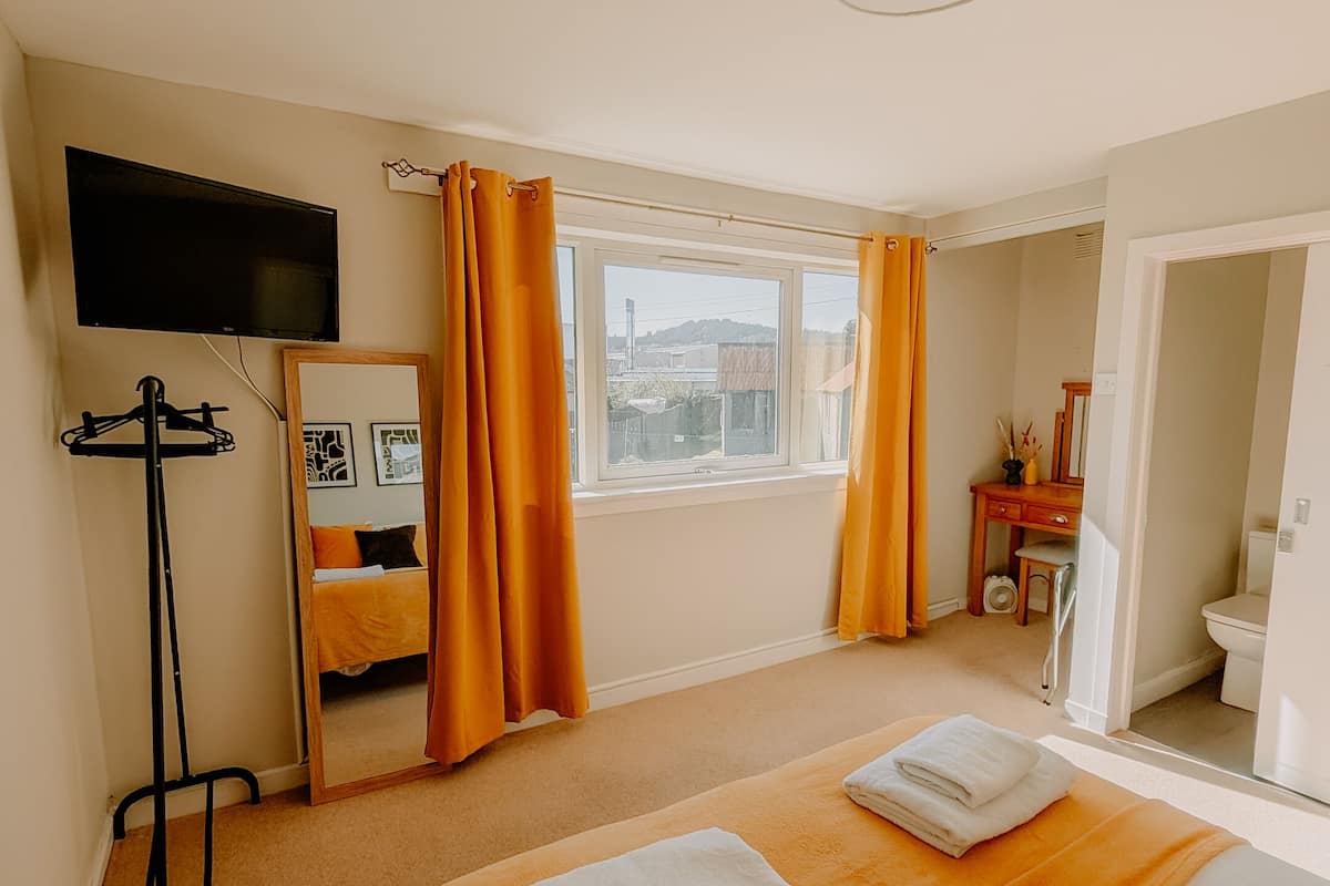 Une chambre d’hôtel avec un lit, une télévision, un bureau et une salle de bain.