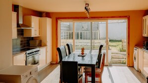 A spacious kitchen with a dining area, a washing machine, and a large window. - Inverness Holiday House (Inverness)