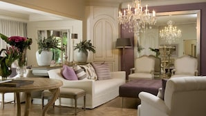 A living room with a white sofa, a round wooden coffee table, and a chandelier. There are two large vases with plants on the coffee table. - Hoeveld House (Sandton)