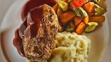 Un plato con filete, puré de papas y verduras asadas.