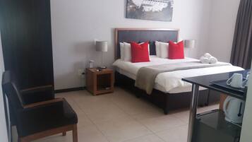 A hotel room with a bed, bedside tables, a desk, and a chair.