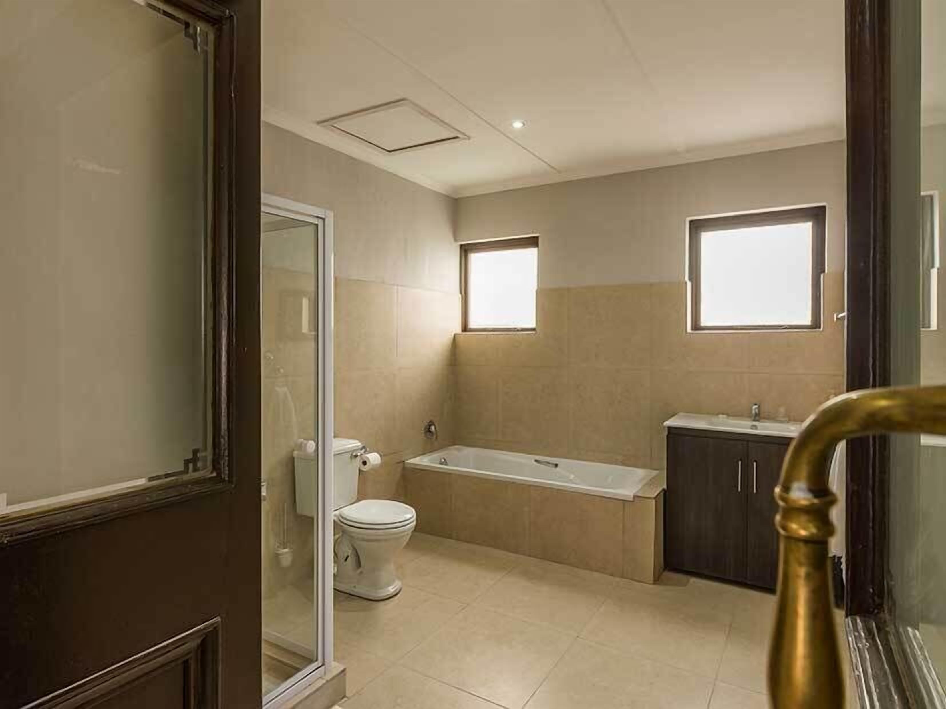 A bathroom with a toilet, bathtub, and a window.