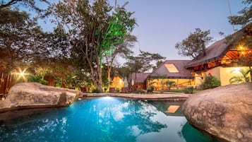 Una piscina al aire libre, sillones reclinables de piscina