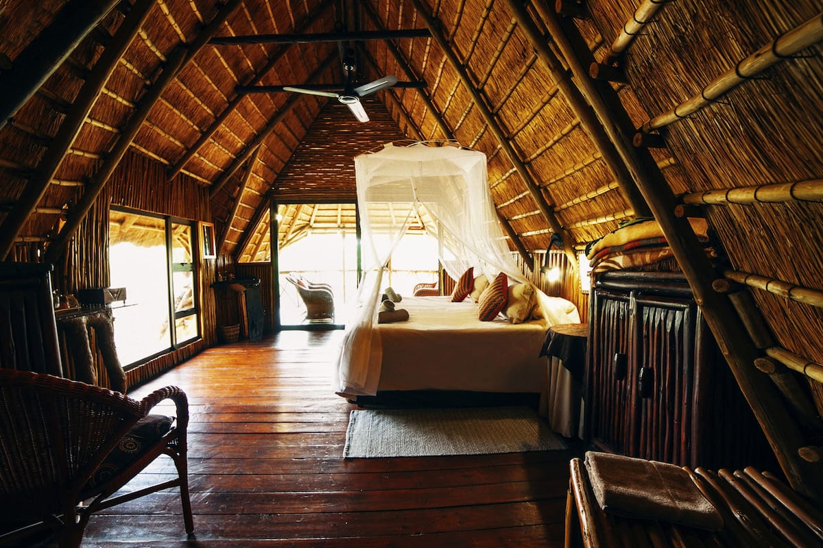 A room with a bed, a chair, a ceiling fan, and a large window.