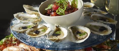 Een visplateau met oesters, kreeft en een saladekom op een blauwe ijsbak.