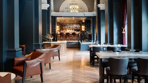 A spacious lobby with high ceilings, elegant chandeliers, and a bar area in the background. - The Darcy Hotel (Washington)
