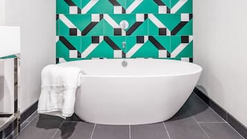 Ein modernes Badezimmer mit einer freistehenden Badewanne, einem Handtuch und einer Wand mit geometrischem Muster.