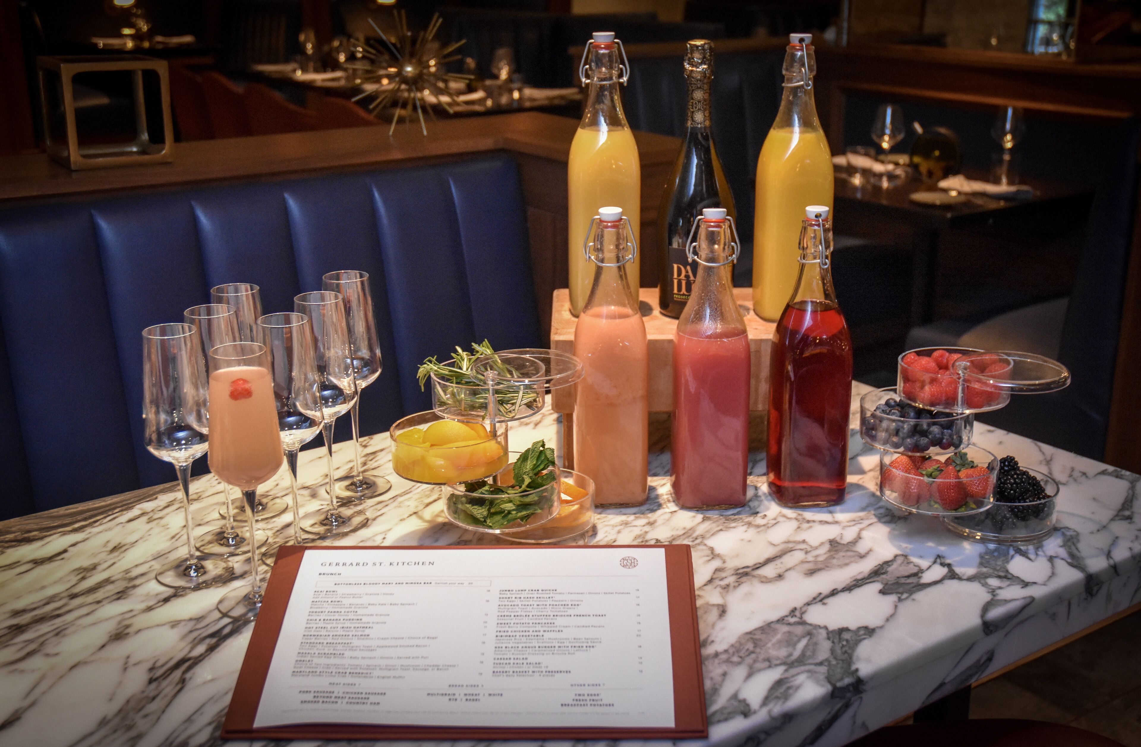 A bar area with a marble countertop, various drinks, and a menu.