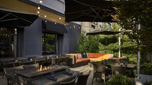 An outdoor patio with a fire feature, seating, and tables. - The Darcy Hotel (Washington)