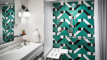 A modern bathroom with a geometric tile backsplash, a white sink, a mirror, and a shower with a glass door.
