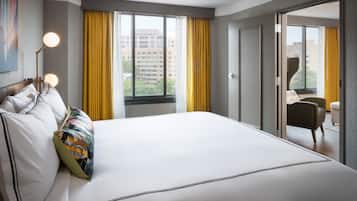 A hotel room with a large bed, a desk, a chair, and a window with curtains.