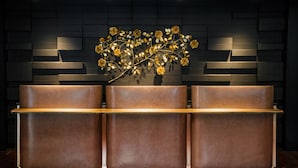 A reception desk with three cushioned seating areas and a decorative floral arrangement on the wall behind. - The Darcy Hotel (Washington)