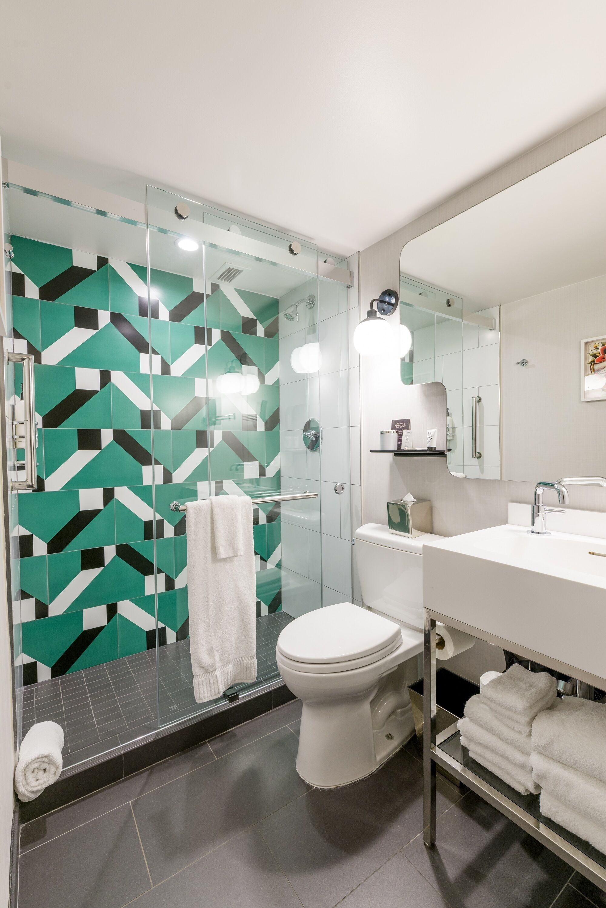 A modern bathroom with a glass shower enclosure, white toilet, and a vanity with a mirror.