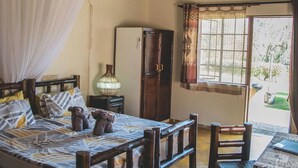 Una habitación con cama, mesita de noche y ventana con cortinas.