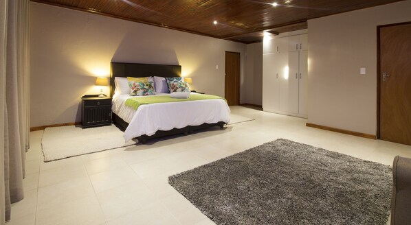 A bedroom with a bed, bedside tables, a wardrobe, and a carpet. - Tsitsikamma Manor (Storms River)