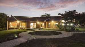 A two-story house with a brick exterior, a circular driveway, and a well-maintained lawn. - Tsitsikamma Manor (Storms River)