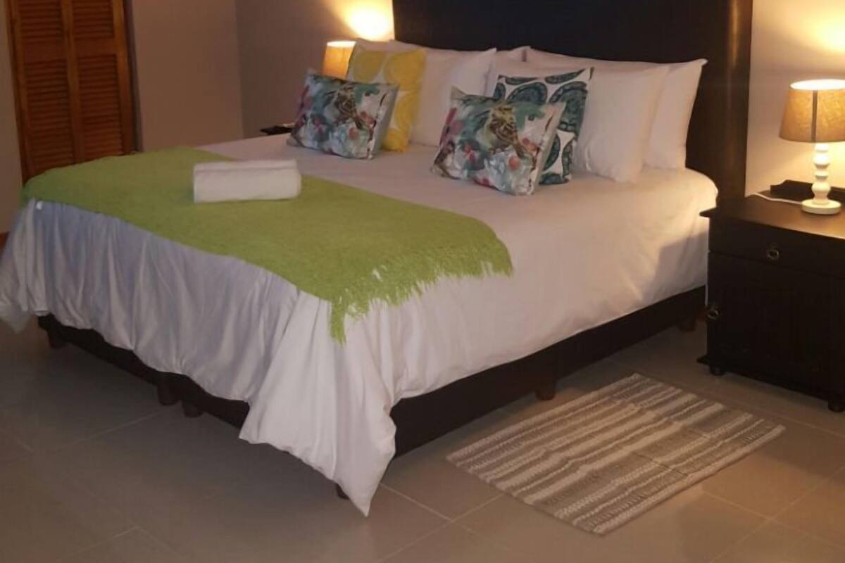 A neatly arranged bedroom with a bed, bedside lamps, and a nightstand.