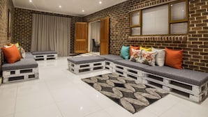A living room with a brick wall, a sofa set, and a patterned rug. - Tsitsikamma Manor (Storms River)