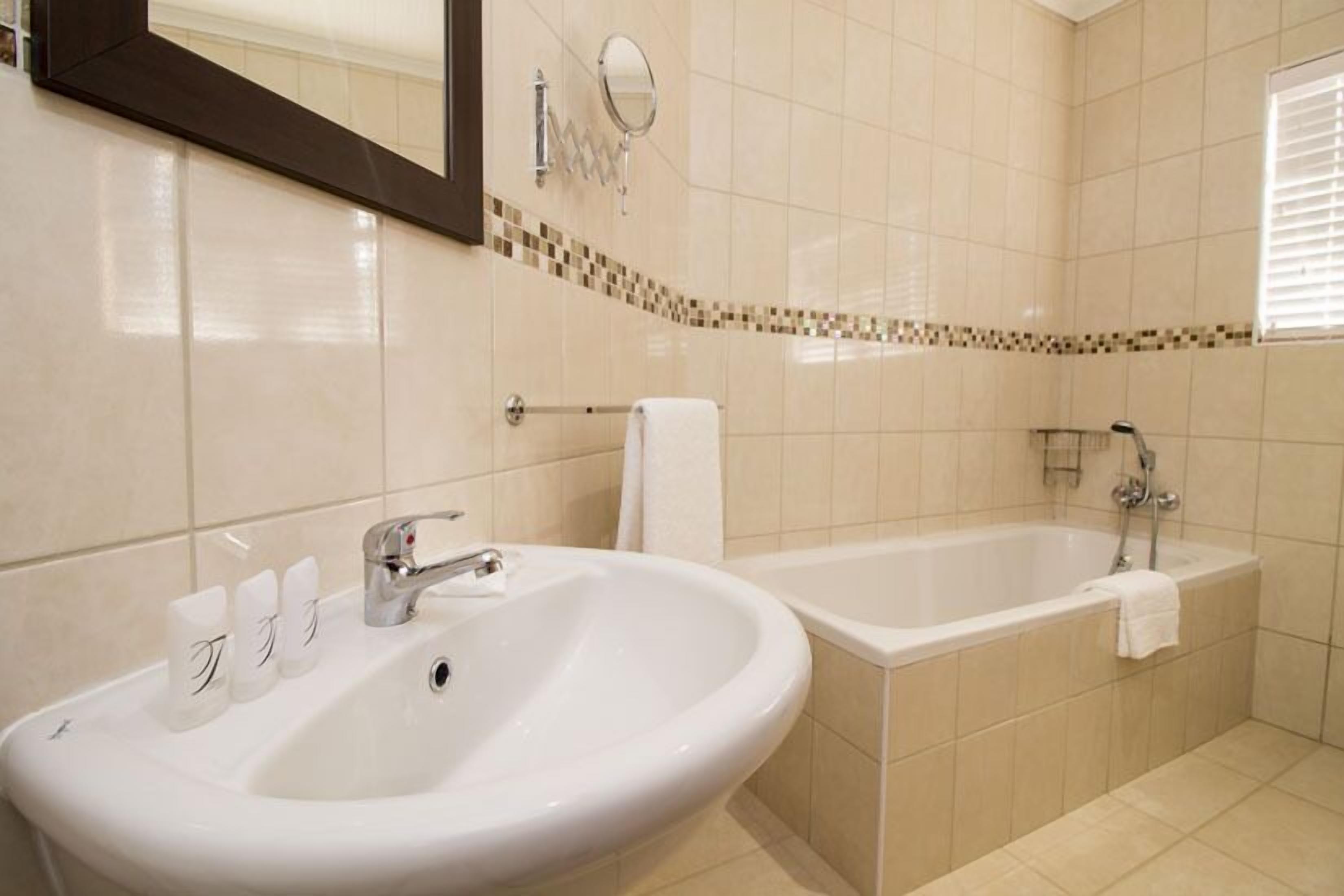 A bathroom with a sink, mirror, and bathtub.