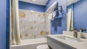 A bathroom with a bathtub, toilet, and a sink with a mirror.