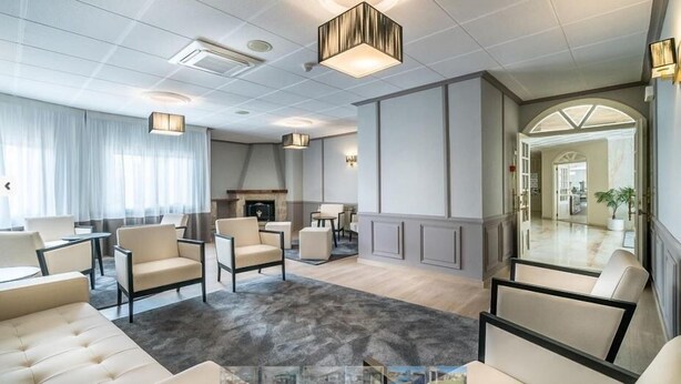 A spacious living area with a fireplace, comfortable seating, and a view of the kitchen. - Ton (Sanxenxo)