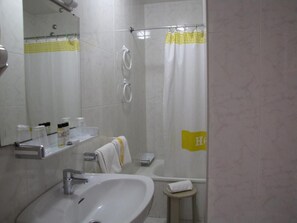 Ein Badezimmer mit Waschbecken, Spiegel, Dusche und Handtuchhalter.