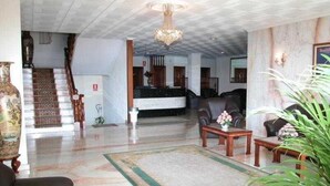 A spacious lobby with a grand staircase, a reception desk, and a seating area with a coffee table and chairs. - Ton (Sanxenxo)