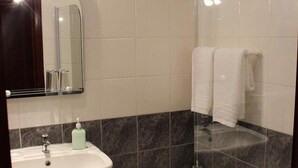 A bathroom with a pedestal sink, a glass-enclosed shower, and a large mirror.