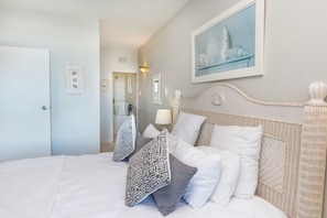 A hotel room with a bed, pillows, a headboard, a painting, and a door. - 43 Sea Lodge (Umhlanga)