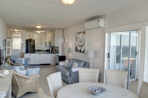 A modern interior with a dining area, kitchen, and a balcony with a view.