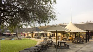 An outdoor patio area with lounge chairs, umbrellas, and tables. - Thabaledi Game Lodge (Beestekraal)