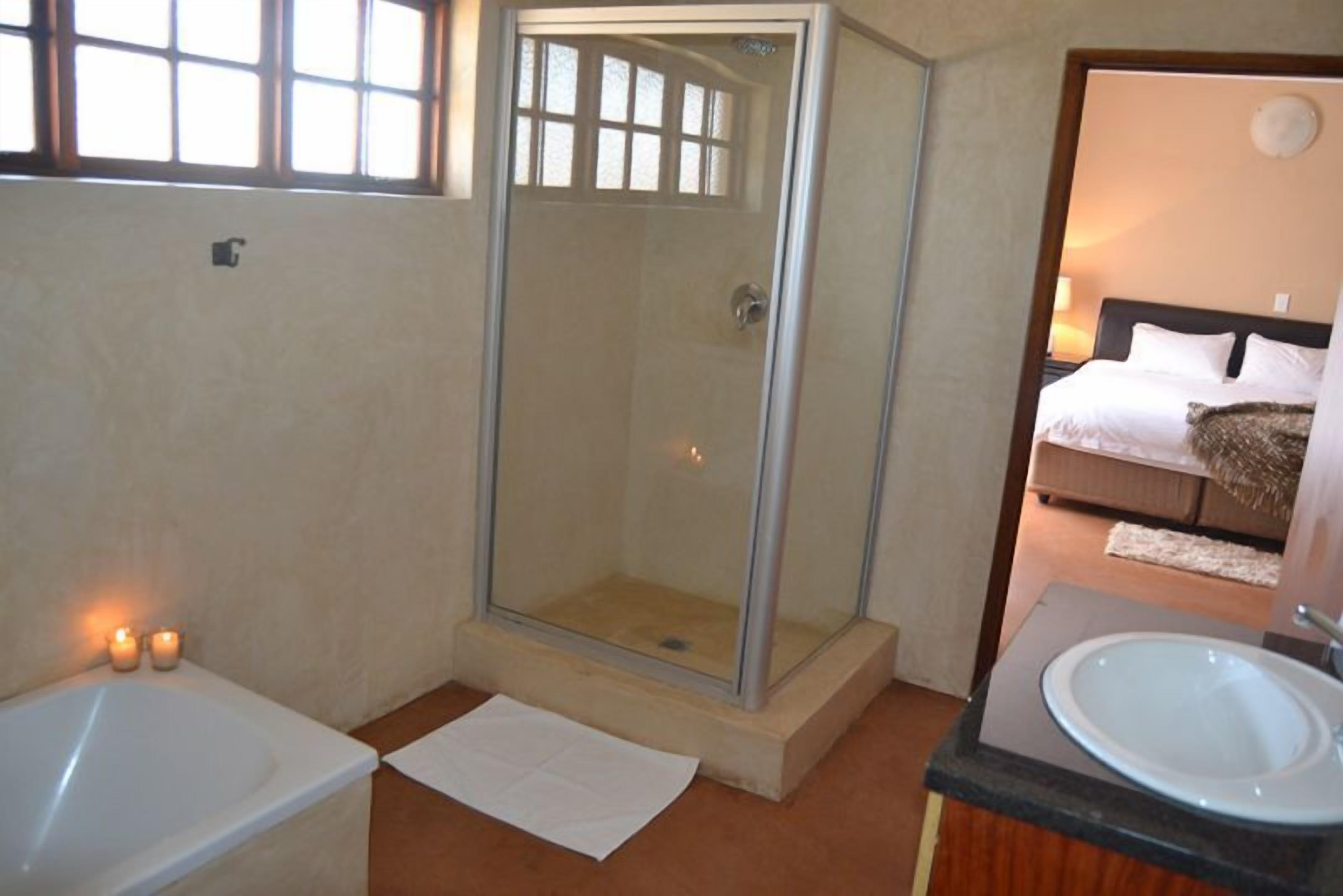 A bathroom with a glass-enclosed shower, a bathtub, and a sink.