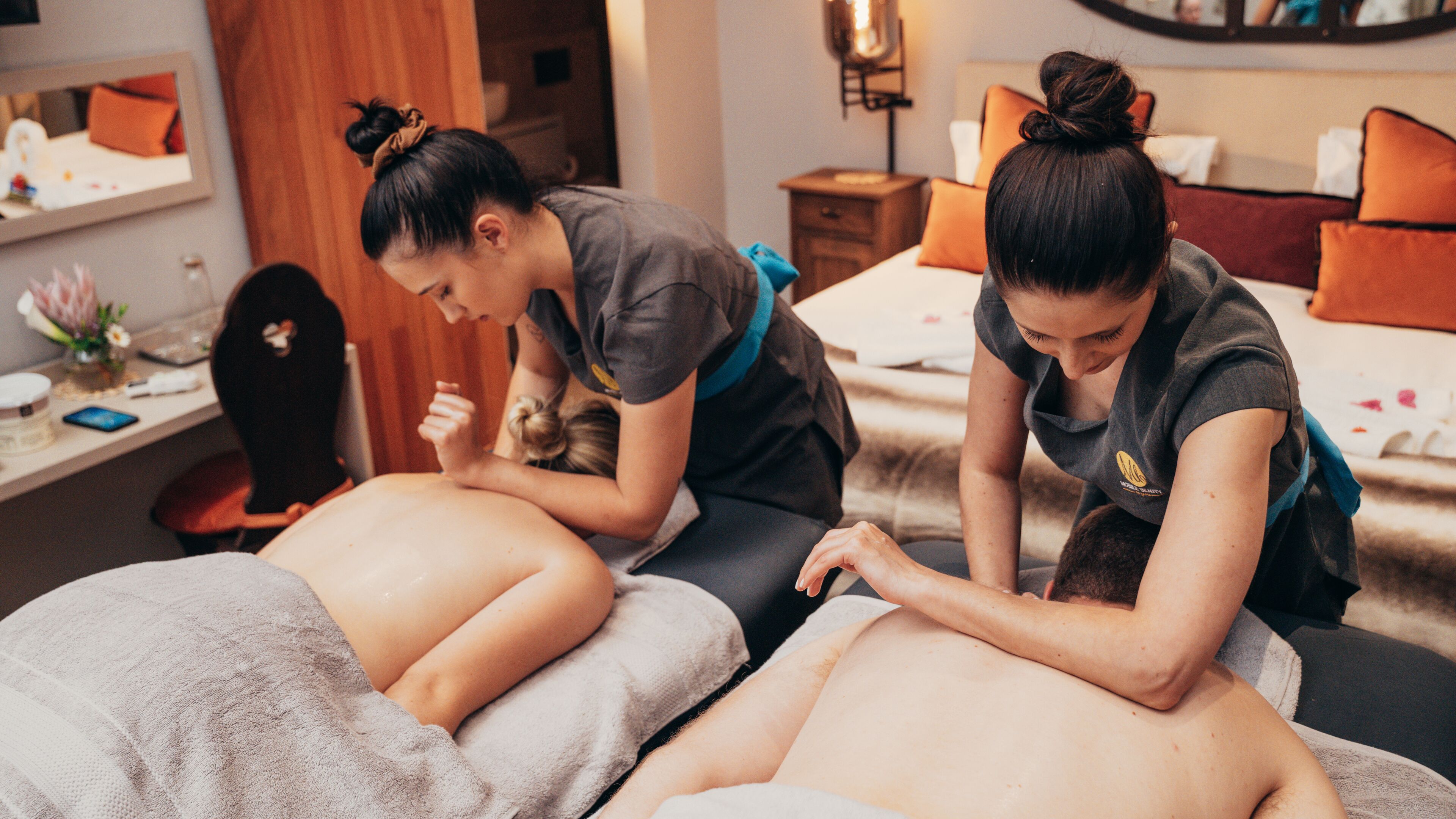 A massage therapy room with two therapists attending to clients.