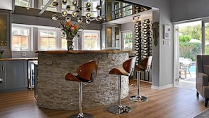 A modern kitchen with a stone island, bar stools, and a hanging light fixture. - Fleur du Soleil (Franschhoek)