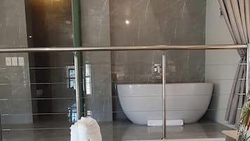 A modern bathroom with a large bathtub, a glass-enclosed shower area, and a balcony with a view.