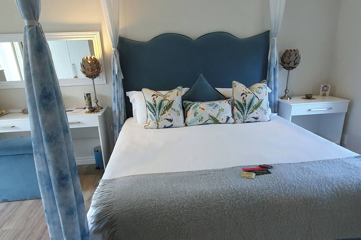 Ein ordentlich eingerichtetes Schlafzimmer mit einem großen Bett, zwei Nachttischen, einem Beistelltisch und einem Schreibtisch.