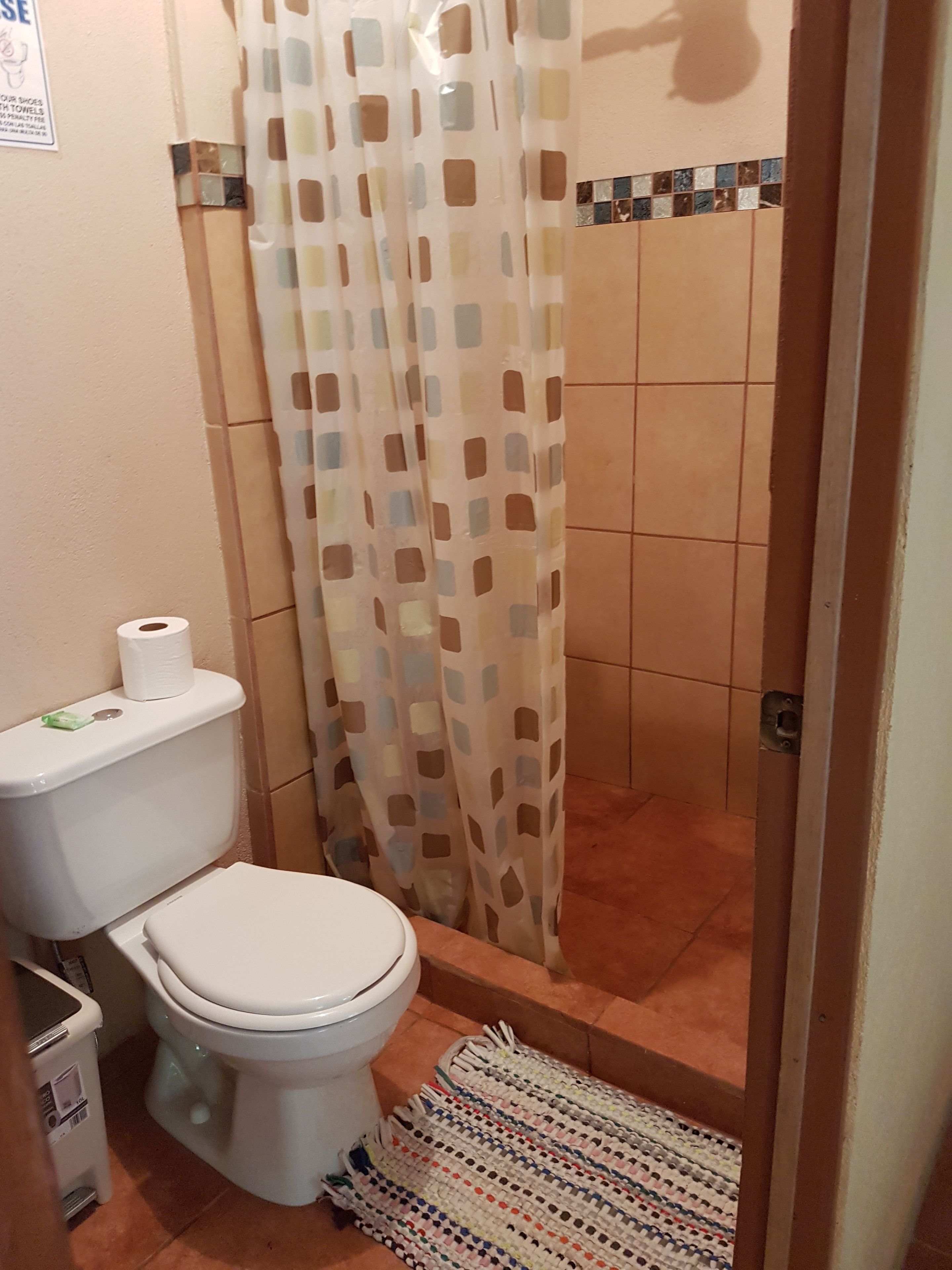 A bathroom with a toilet, a shower curtain, and a tiled floor.