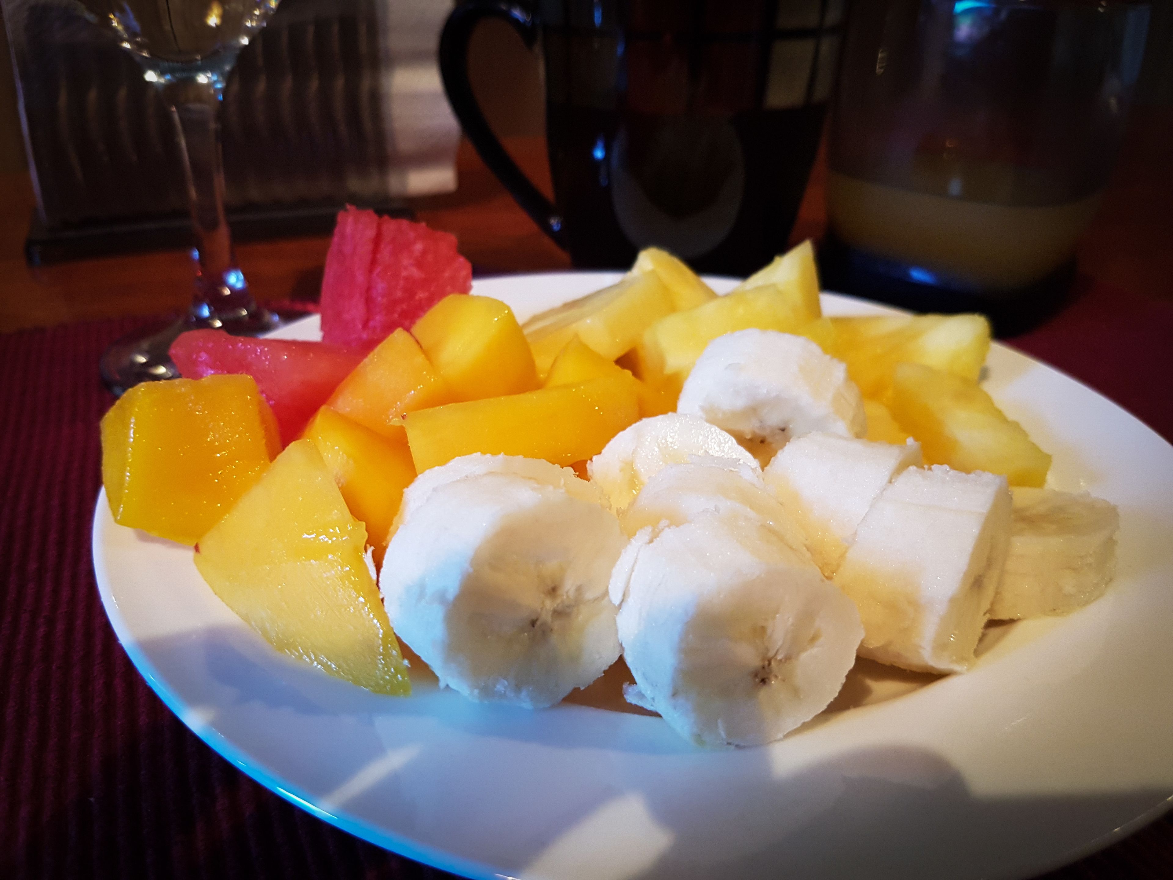A plate of fruit including bananas, mangoes, and watermelon.
