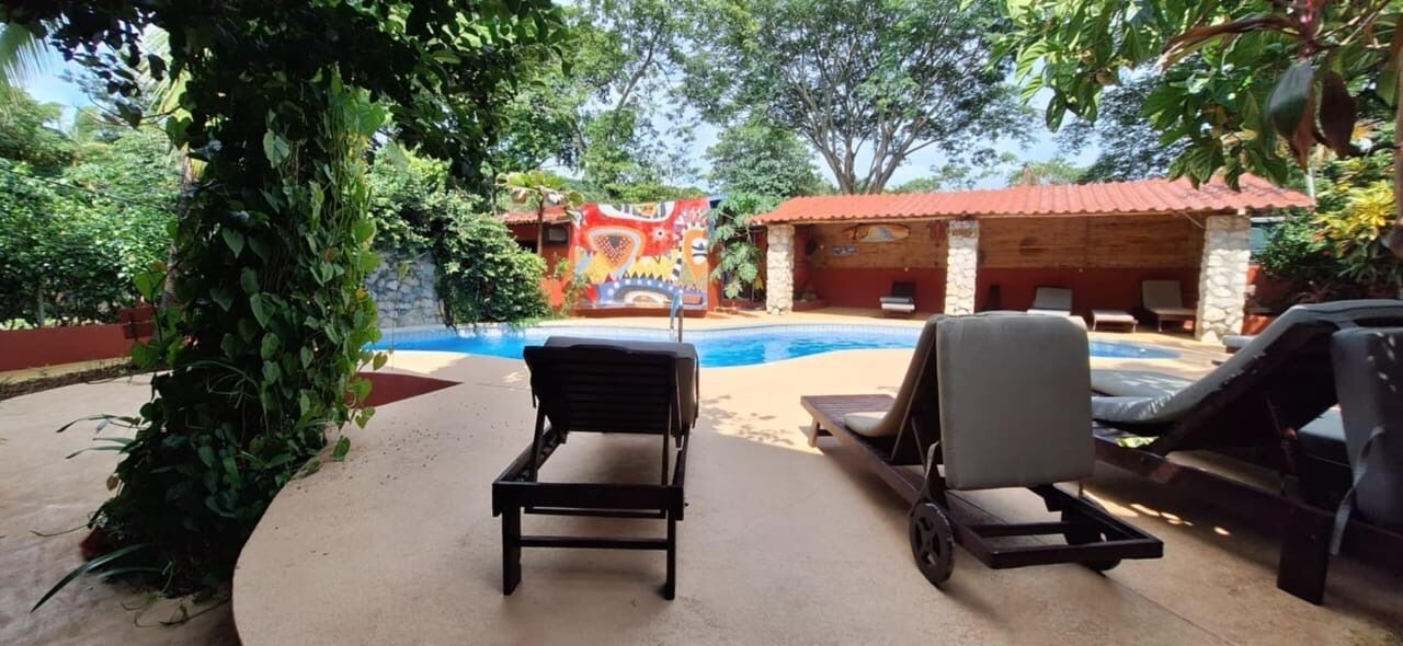 Un espace aménagé au bord de la piscine, avec des chaises longues et une fresque murale en arrière-plan.