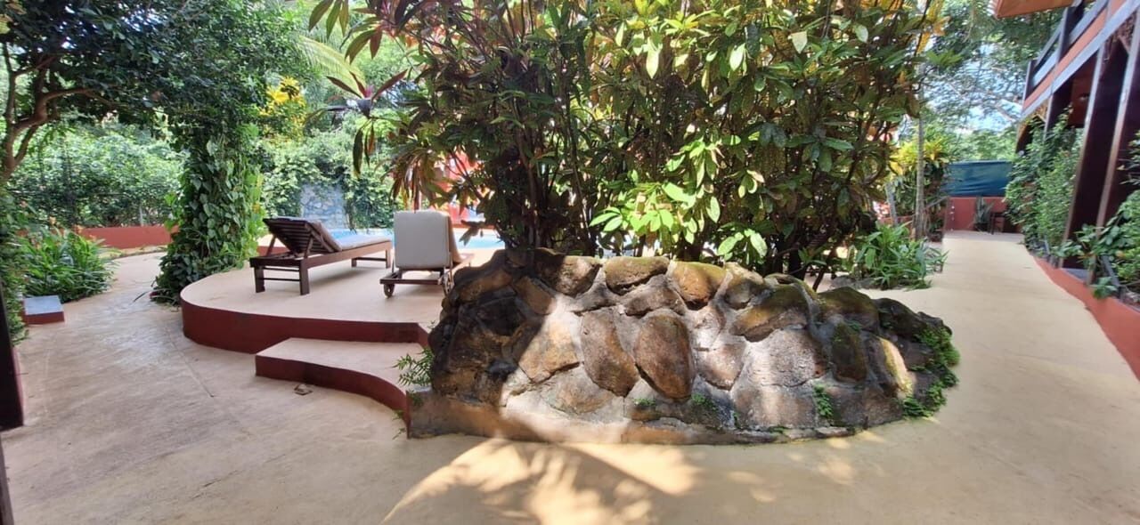 A stone wall with a curved seating area and a pool in the background.