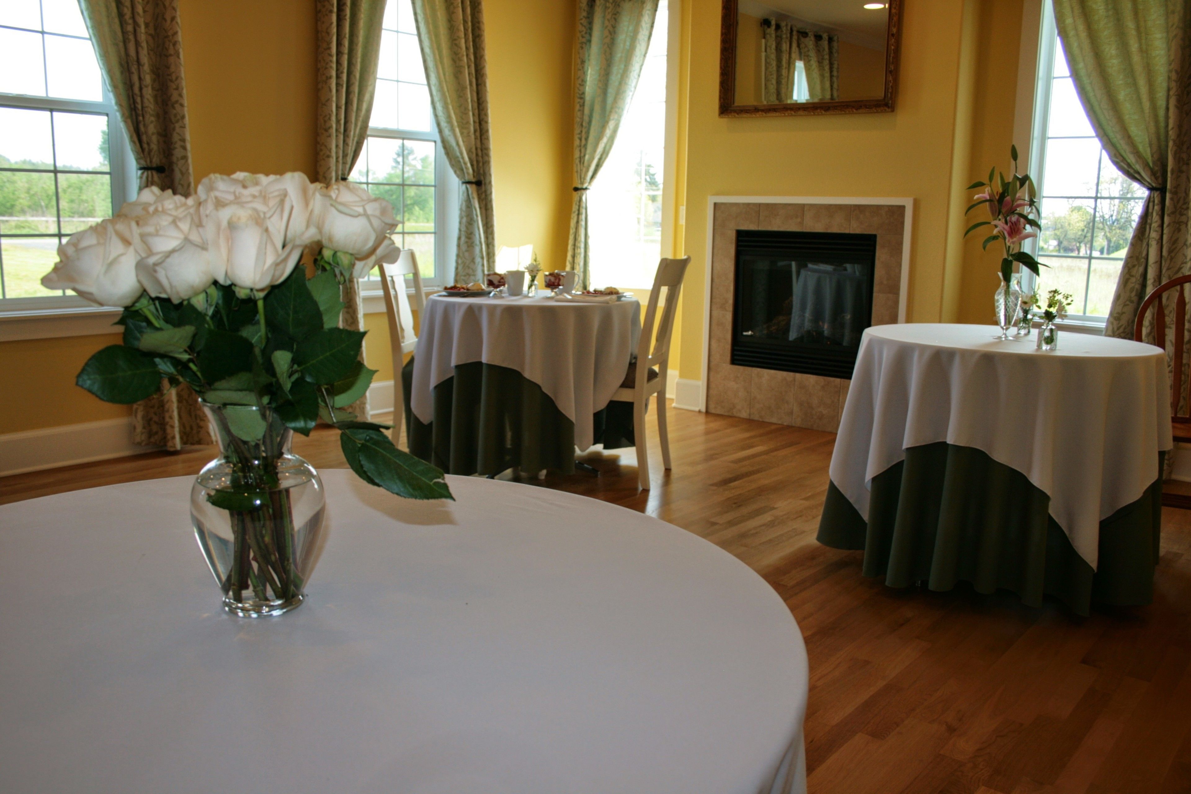 A dining area with round tables, chairs, and a fireplace.