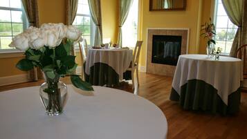A dining area with round tables, chairs, and a fireplace.