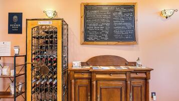 A wine rack with bottles, a wooden cabinet, and a chalkboard menu listing wines and prices.