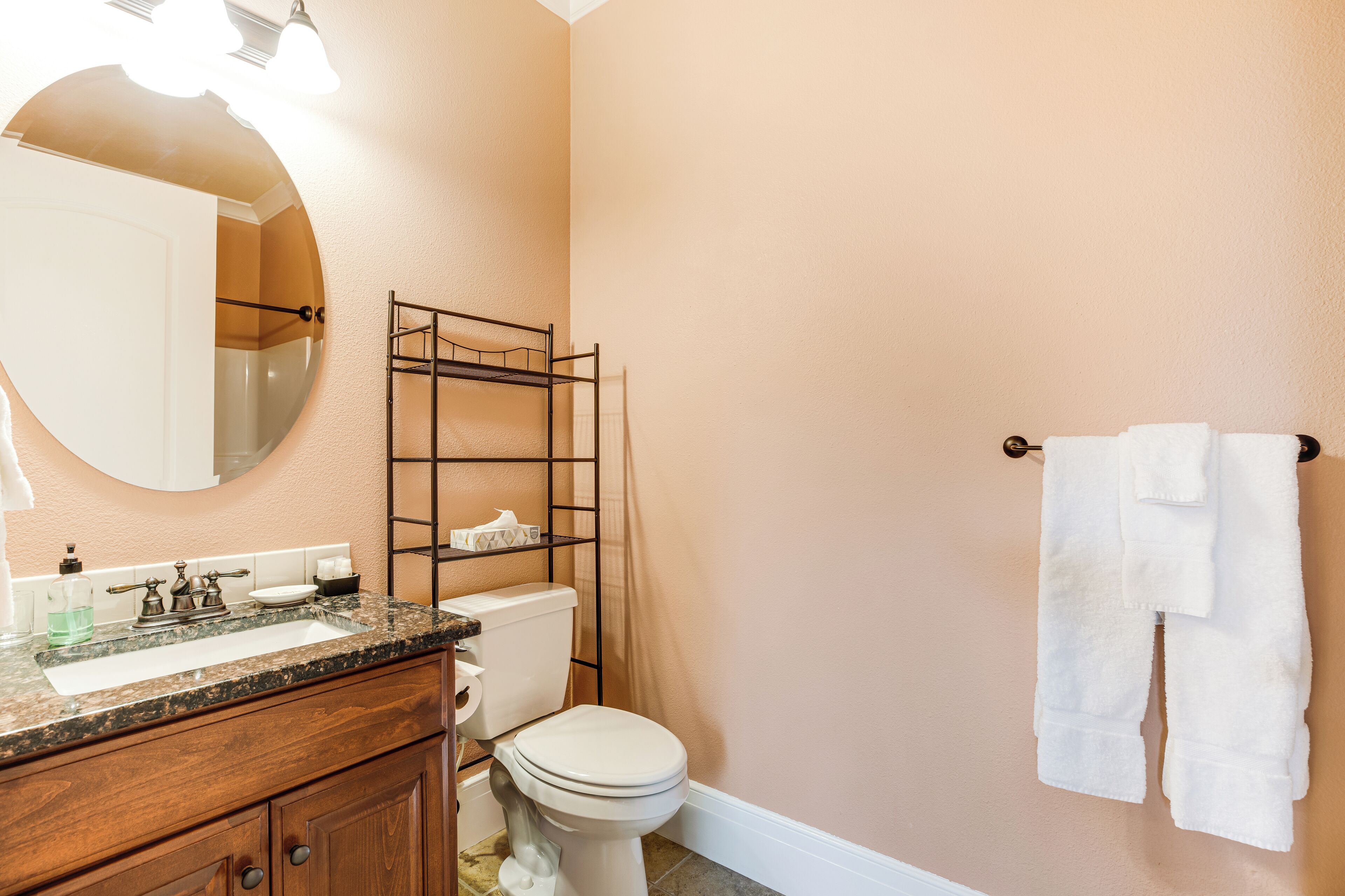 Une salle de bain équipée d’un meuble-lavabo, d’un lavabo, d’un miroir, de toilettes et d’un porte-serviettes.