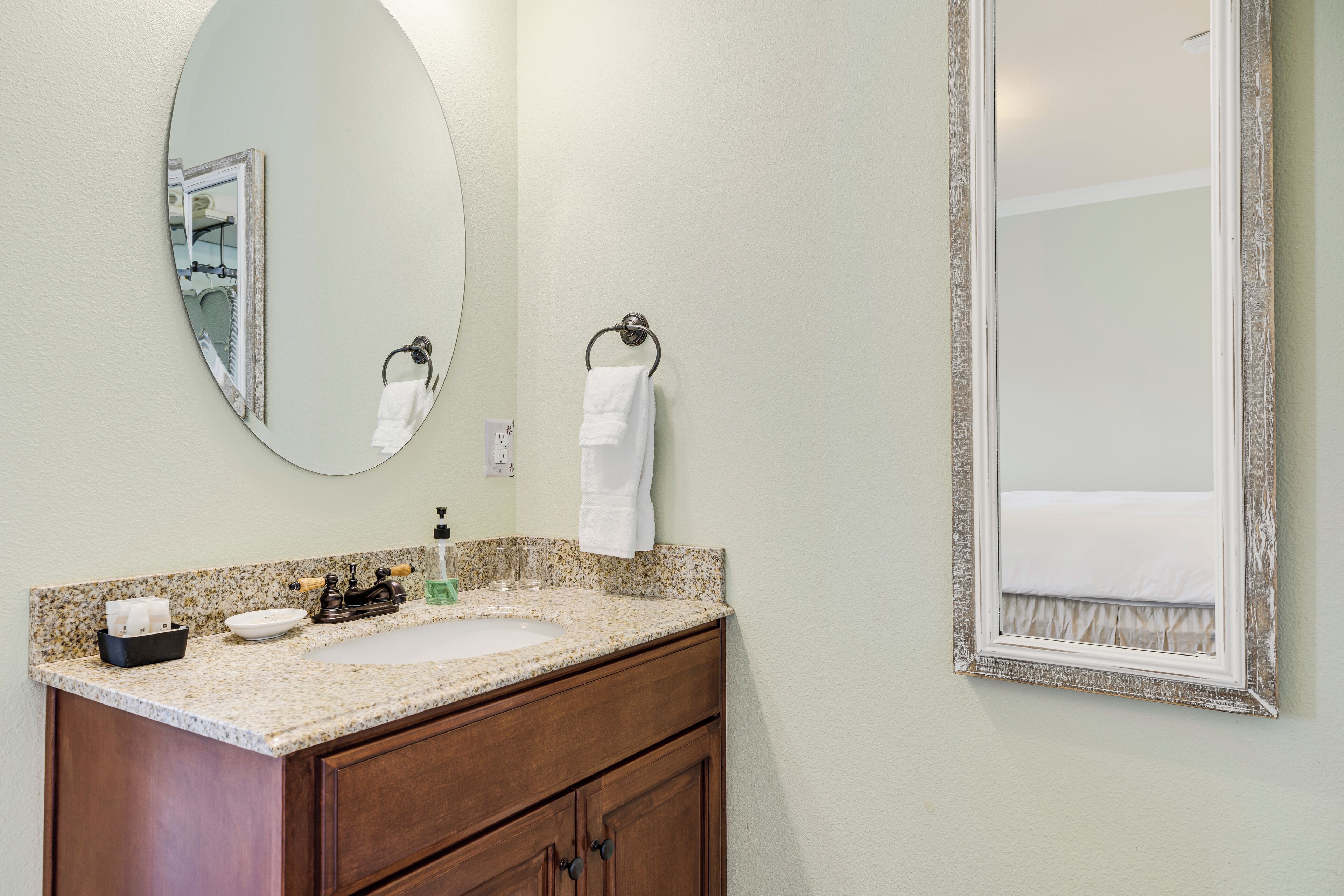 A bathroom with a sink, mirror, and towel rack.